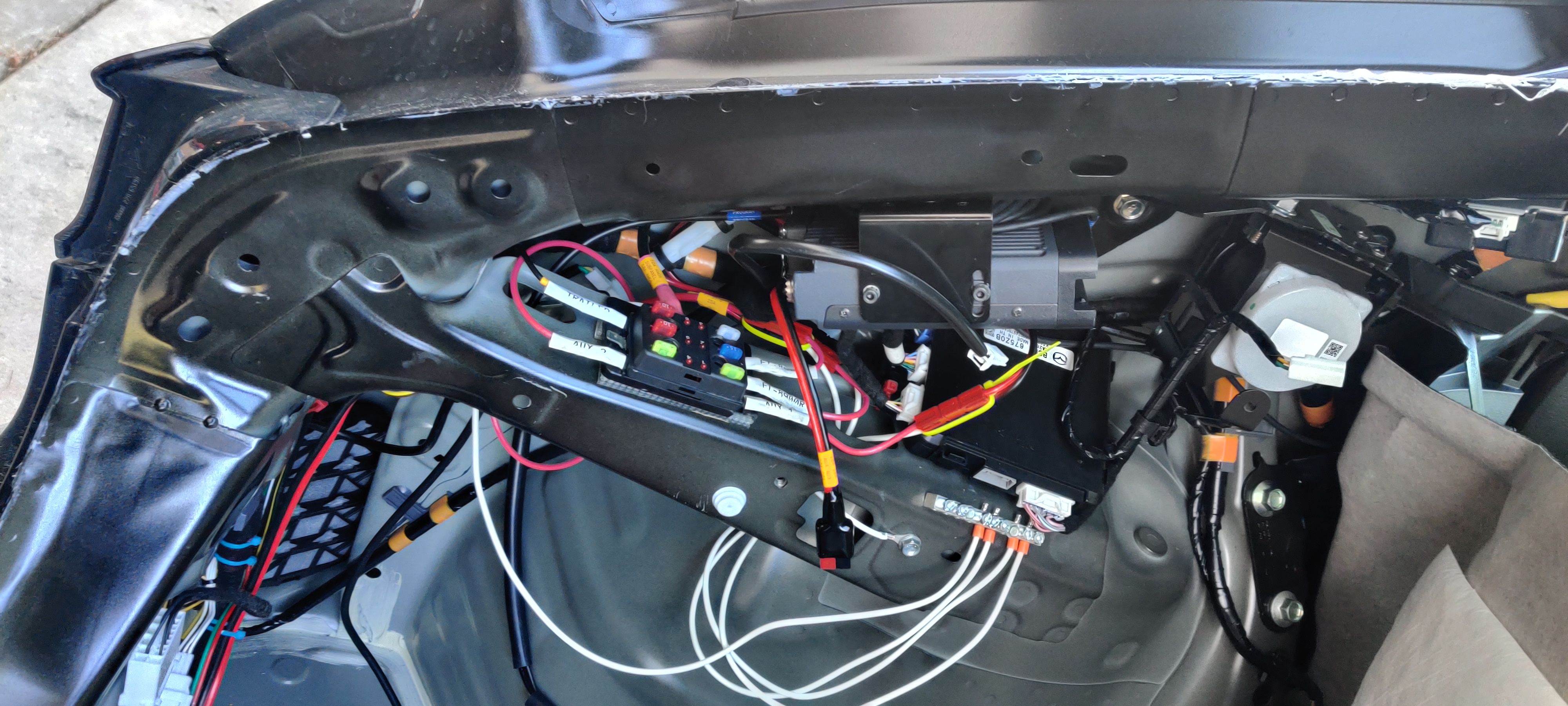 FT-8900R mounted on diagonal frame rail over shelf and subpanel. White flying connector is for cargo area LED; flying PowerPole is 20A auxiliary for cargo area. Ziptied PowerPole over OEM module is feed for FT-857D on the other side of the car; the one under the FT-8900R is for that radio.